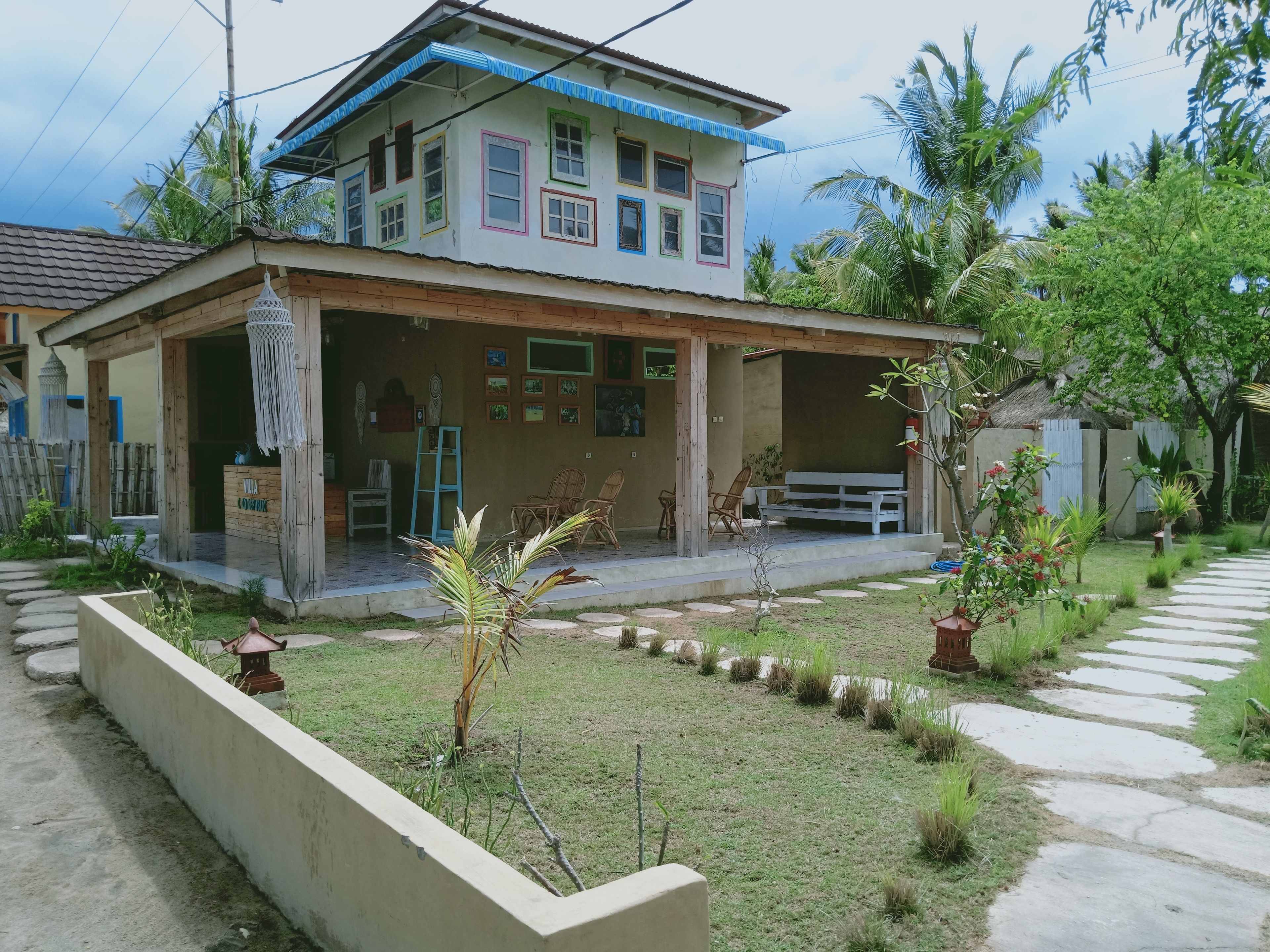 A two-story house with a covered porch, a small garden, and a pathway leading to the entrance.