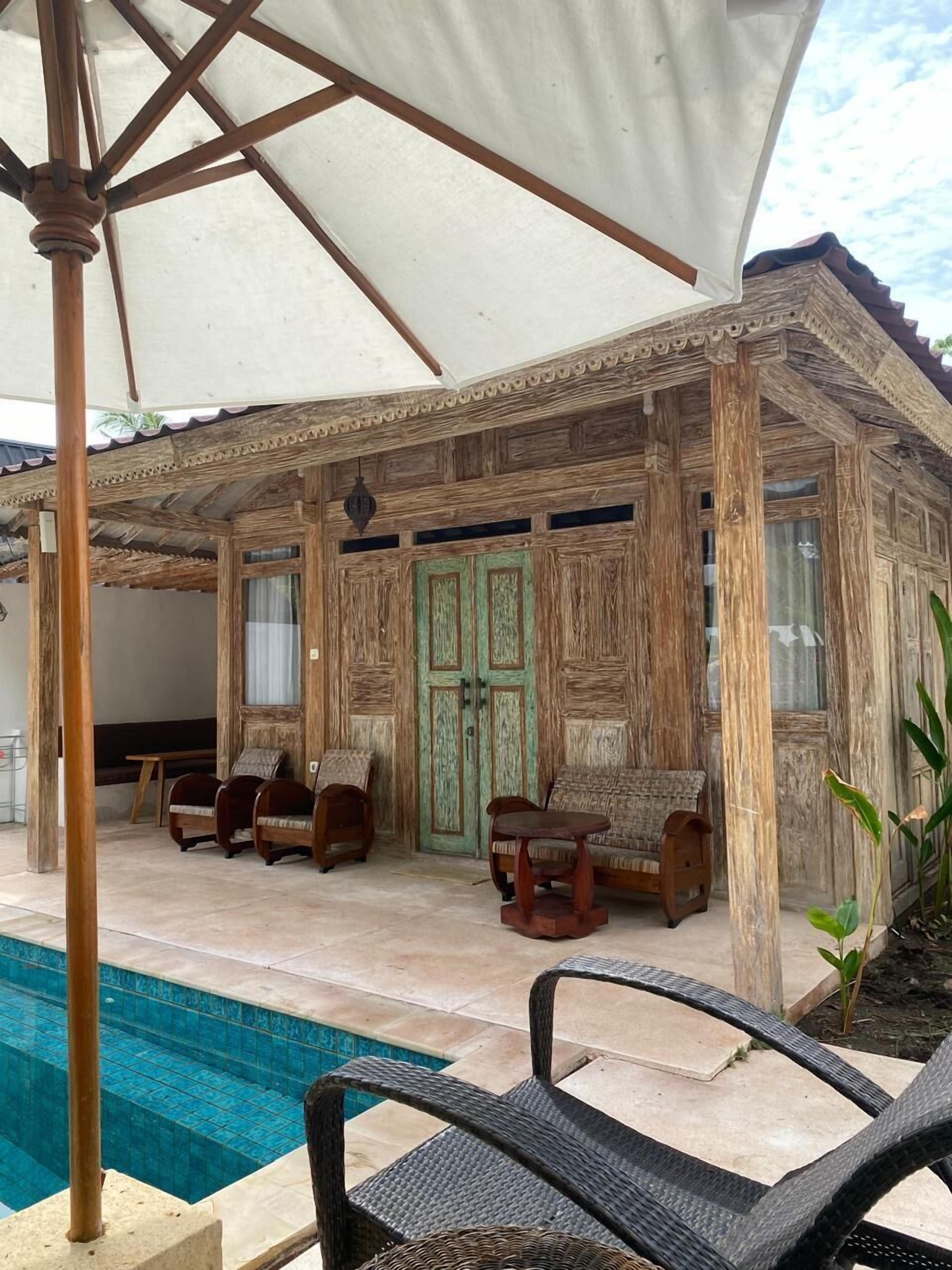 Une structure en bois dotée d’une piscine, comprenant un espace extérieur aménagé pour s’asseoir et une zone couverte.