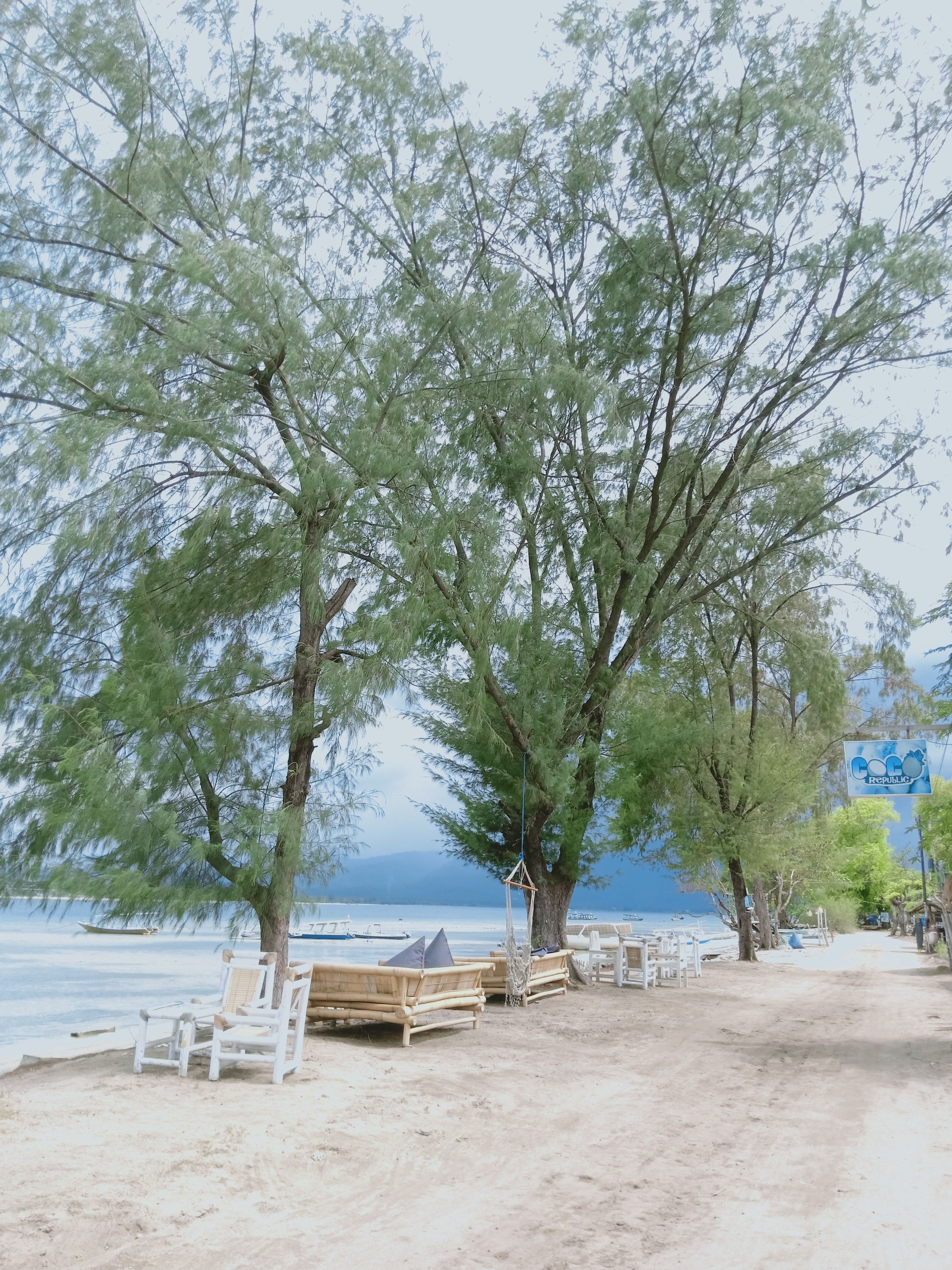 A beach with wooden lounge chairs and a swing.
