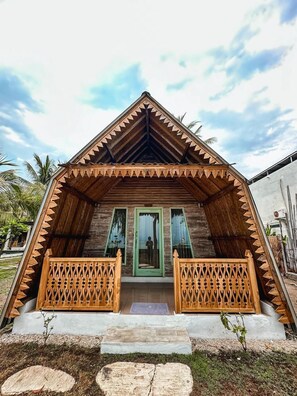 A wooden house with a triangular roof and a porch with wooden railings. - Villa Coco Republic (Gili Air)