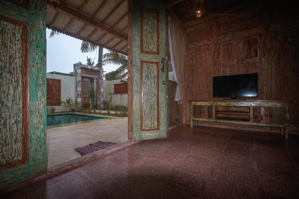Quarto com piscina, paredes de madeira e televisão.