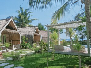 A resort with thatched-roof cottages and a covered seating area with a pool. - Villa Coco Republic (Gili Air)