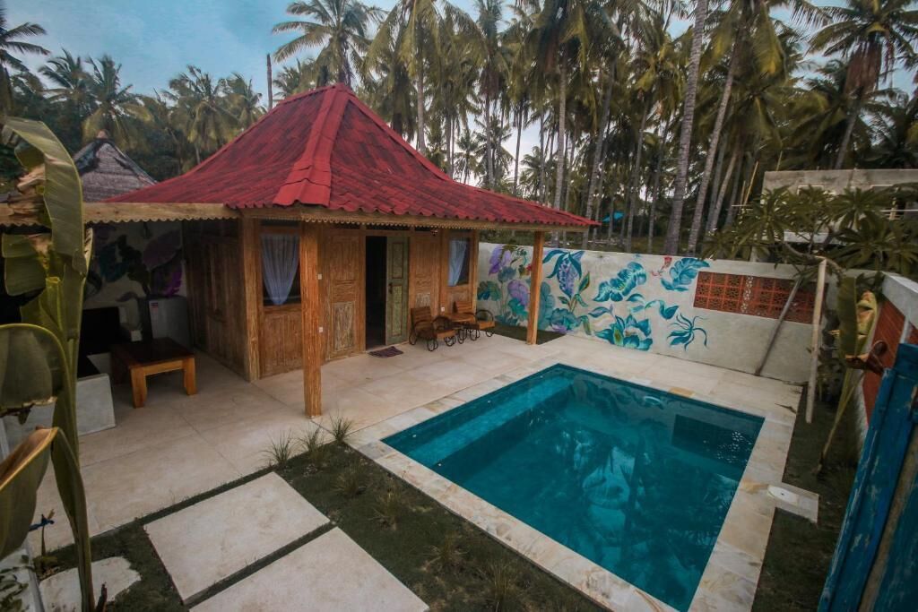 A small house with a red roof, a swimming pool, and a mural on the wall.
