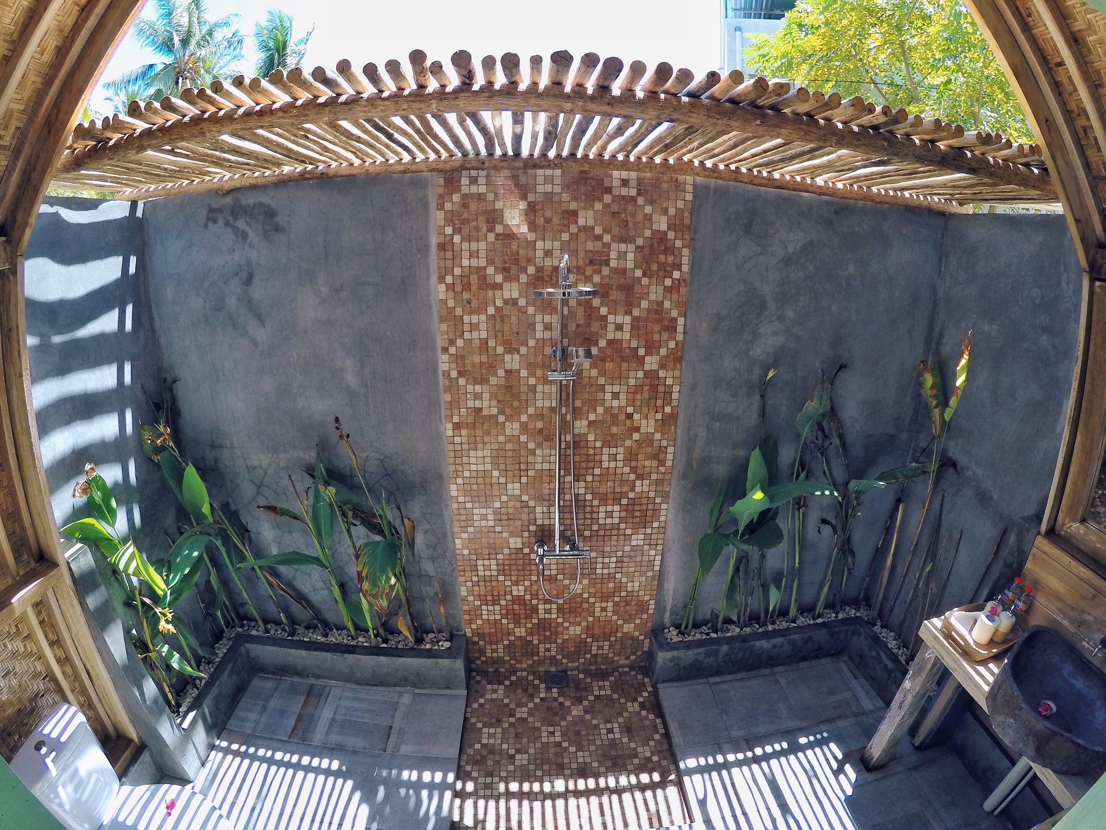 Un baño con pared de mosaico de azulejos, ducha y lavamanos.