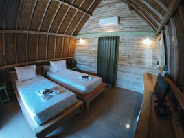 Una habitación acogedora con dos camas, techo de madera, cortina verde y un televisor sobre un mueble de madera.