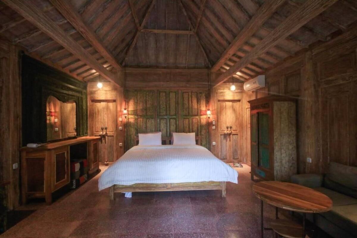 Una habitación rústica de madera con una cama grande, paredes de madera y un techo con vigas a la vista.