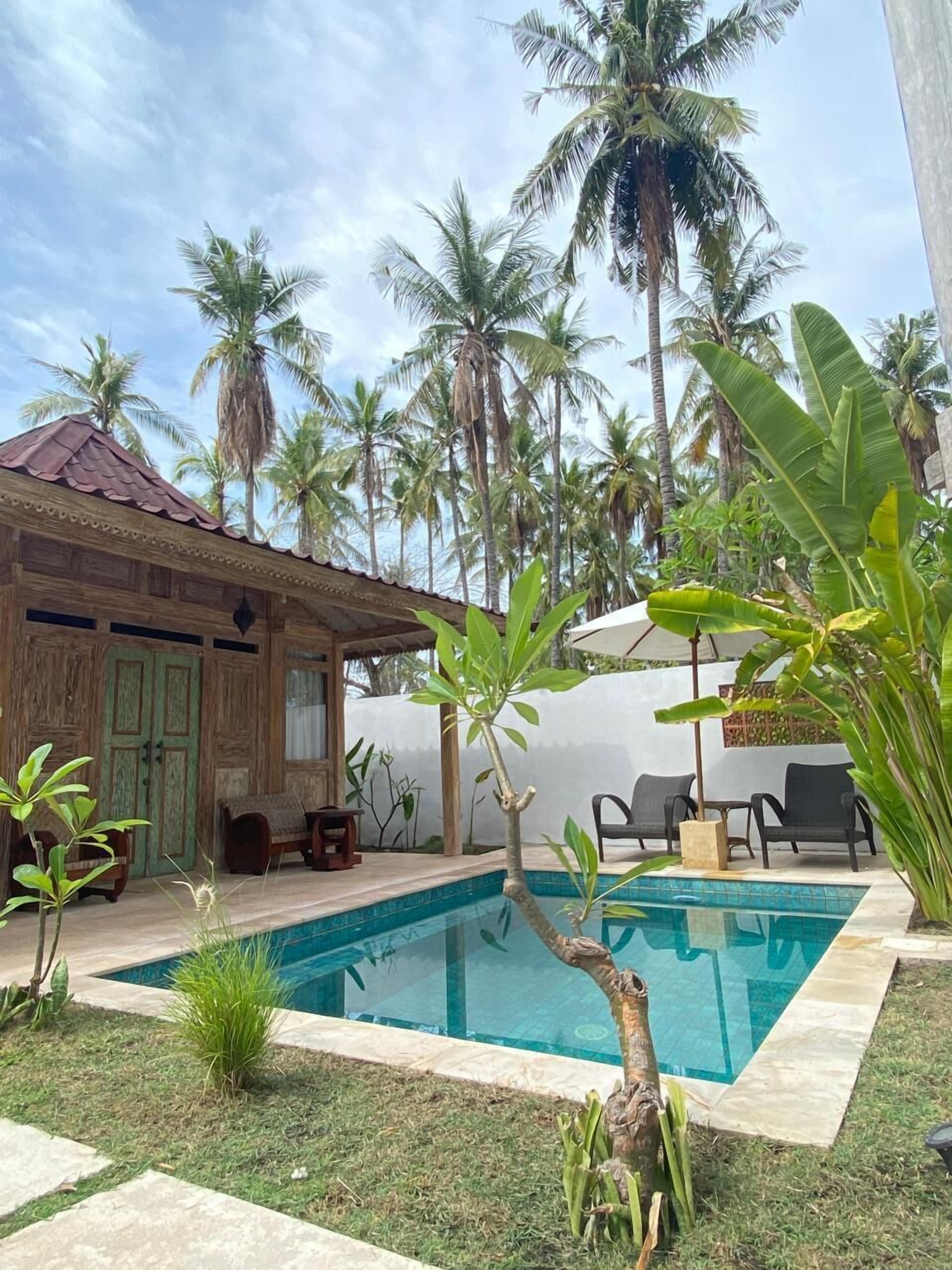 A pool area with a wooden structure, palm trees, and outdoor seating.