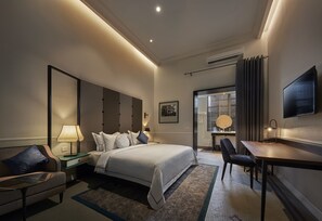 A modern hotel room with a large bed, bedside tables, a desk, and a flat-screen TV. - The Edison George Town (George Town)