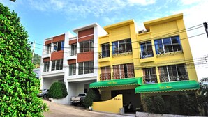 Una hilera de edificios coloridos con balcones, un toldo verde y un cielo despejado.