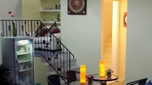 Comedor con mesas y sillas redondas, una escalera y un refrigerador.