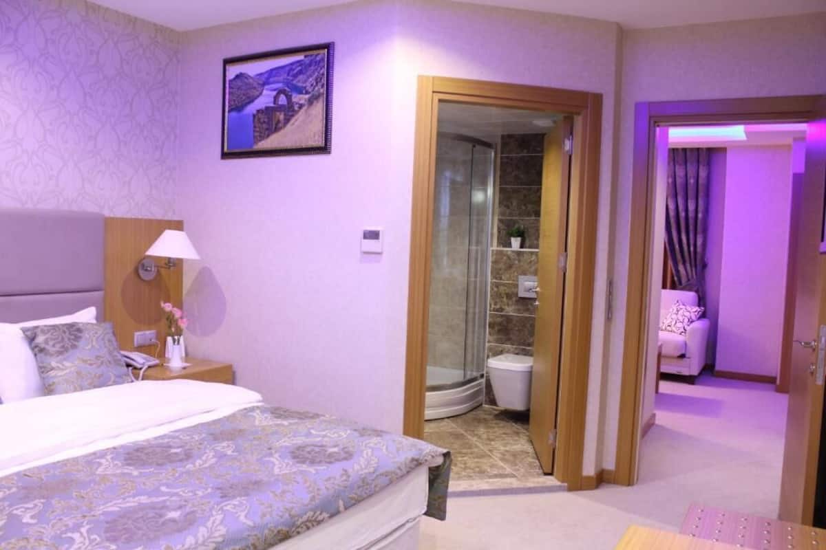 Ein Hotelzimmer mit Bett, Nachttisch, Lampe, Duschbereich und Badezimmer.