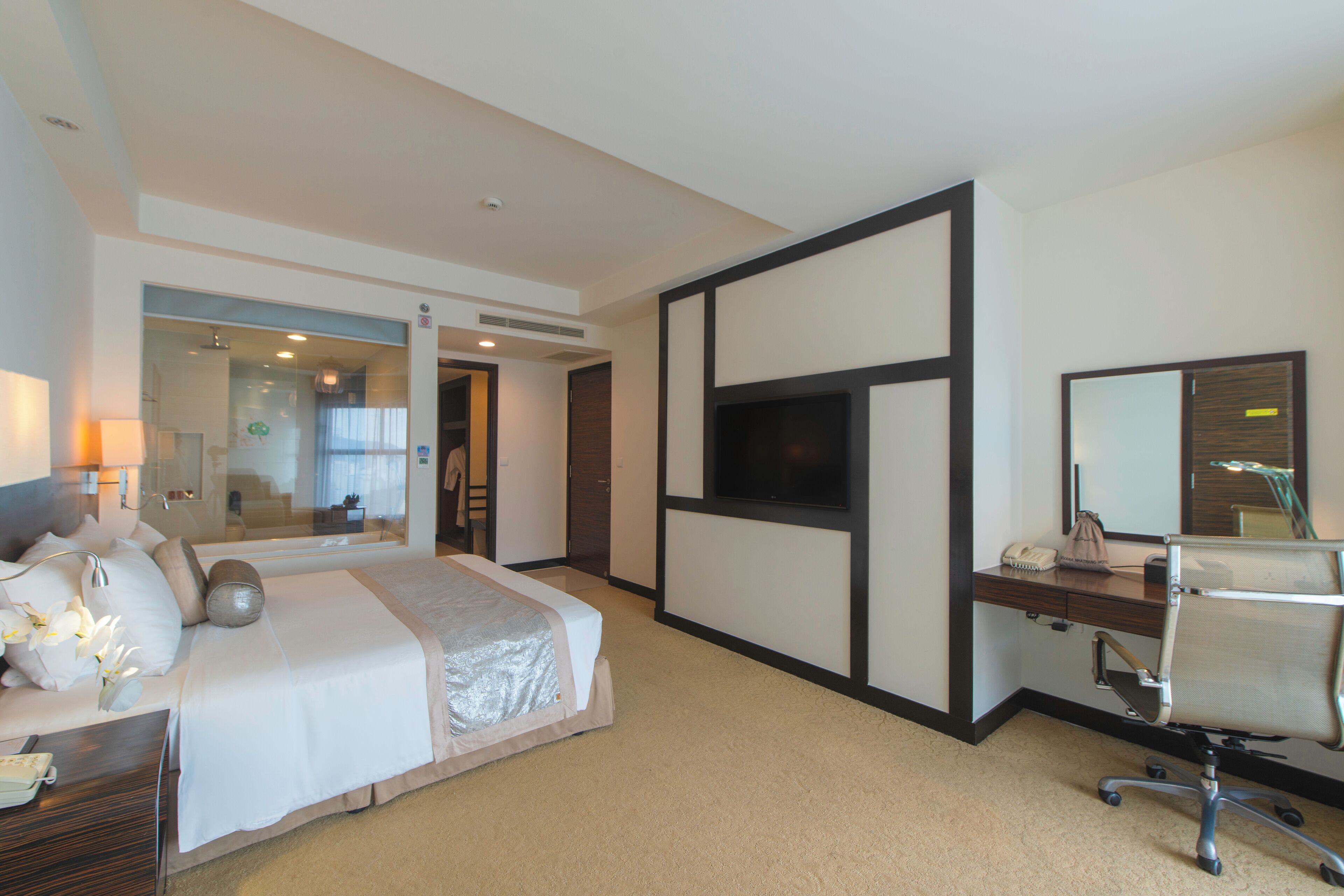 A hotel room with a bed, desk, chair, and TV.