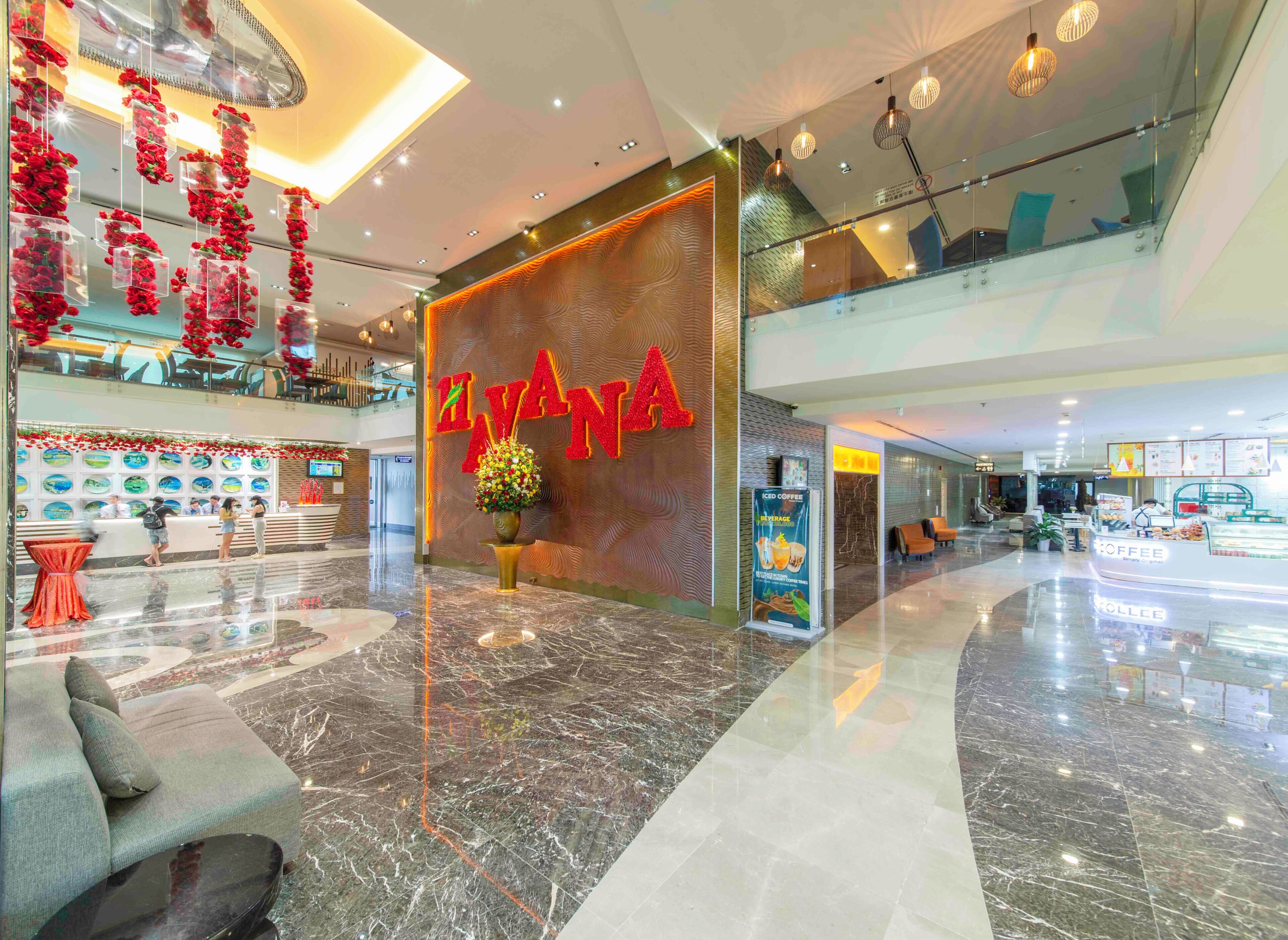 A modern hotel lobby with a reception desk, a seating area, and a coffee shop.