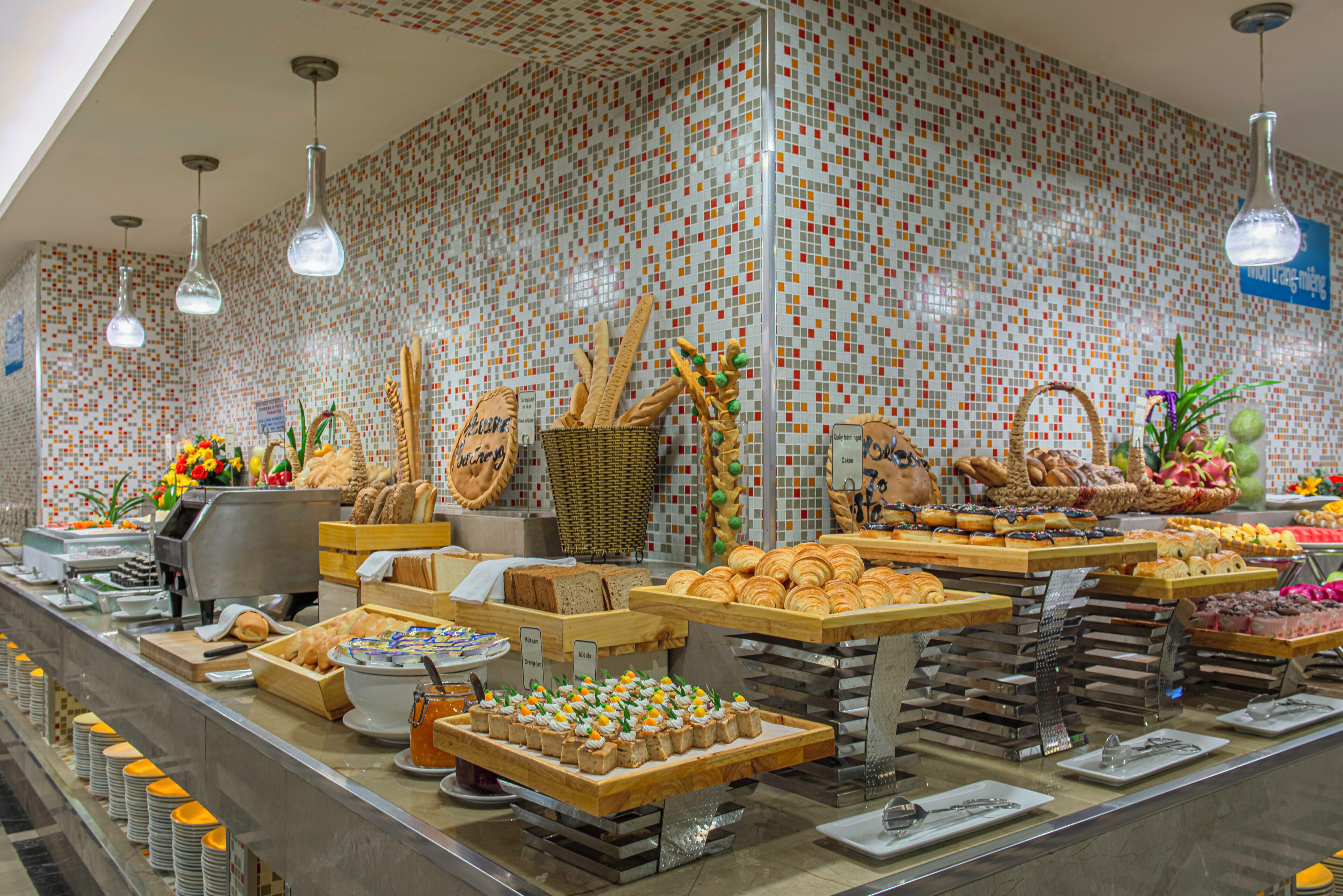 Buffet com diversos alimentos e painel de azulejos.