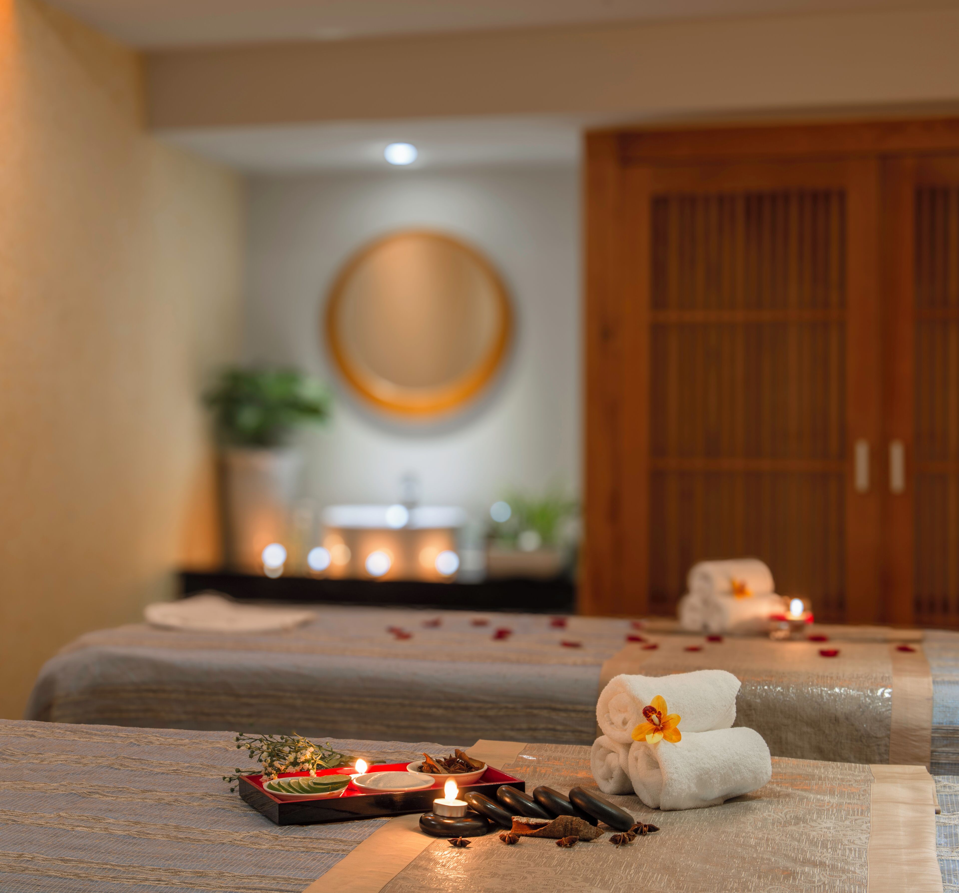 Een spa-ruimte met twee massagetafels, kaarsen en handdoeken.