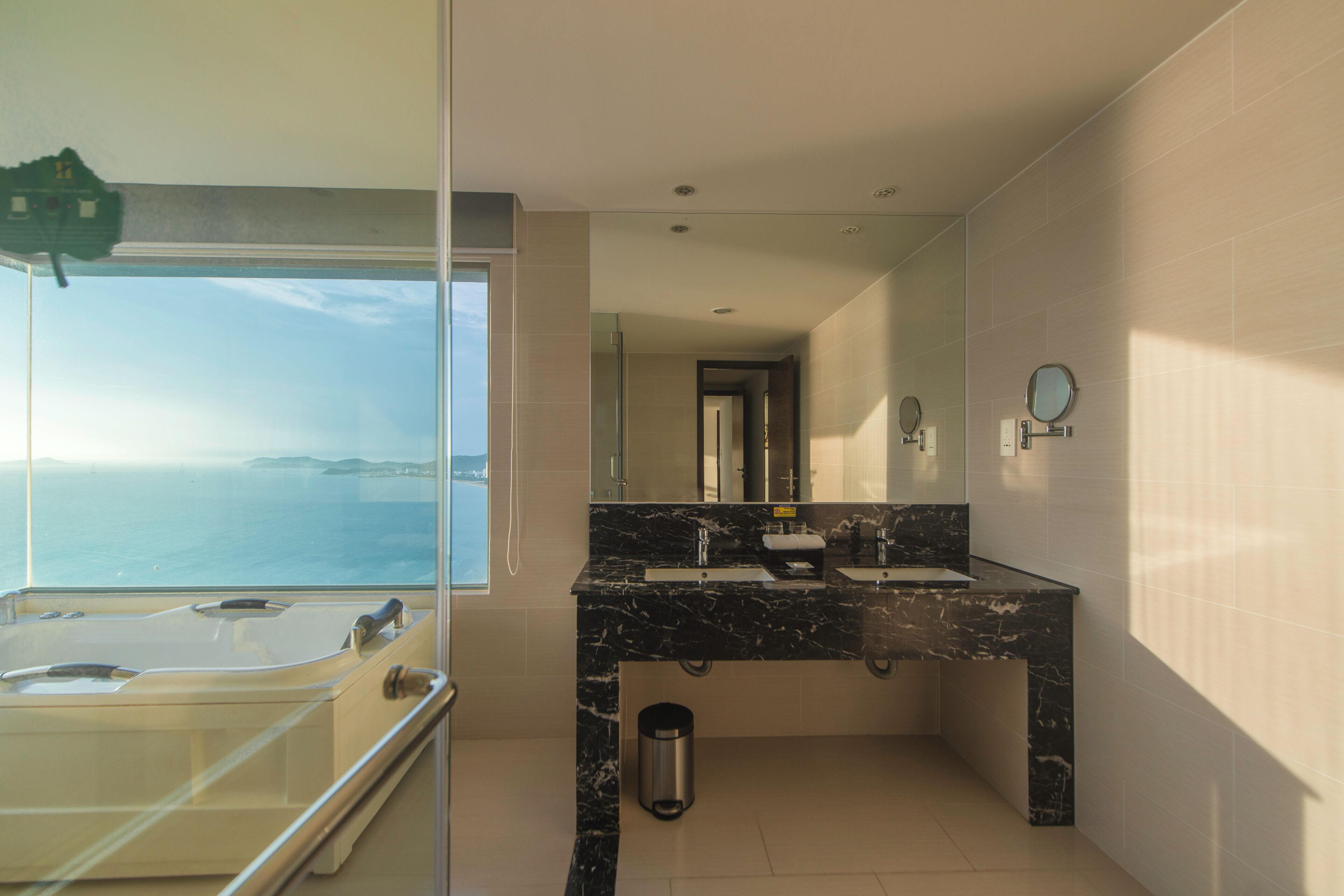 Une salle de bain dotée d’une grande fenêtre, d’un double lavabo et d’un espace douche.