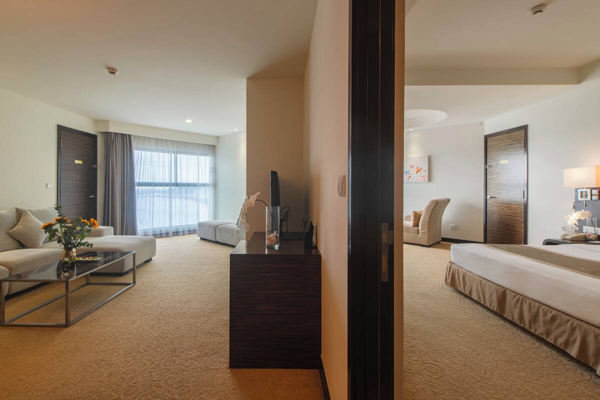 A hotel room with a bed, a sofa, a coffee table, and a desk.