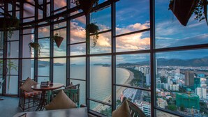 A high-rise room with a large window overlooking a cityscape and a body of water. - Premier Havana Hotel (Nha Trang)