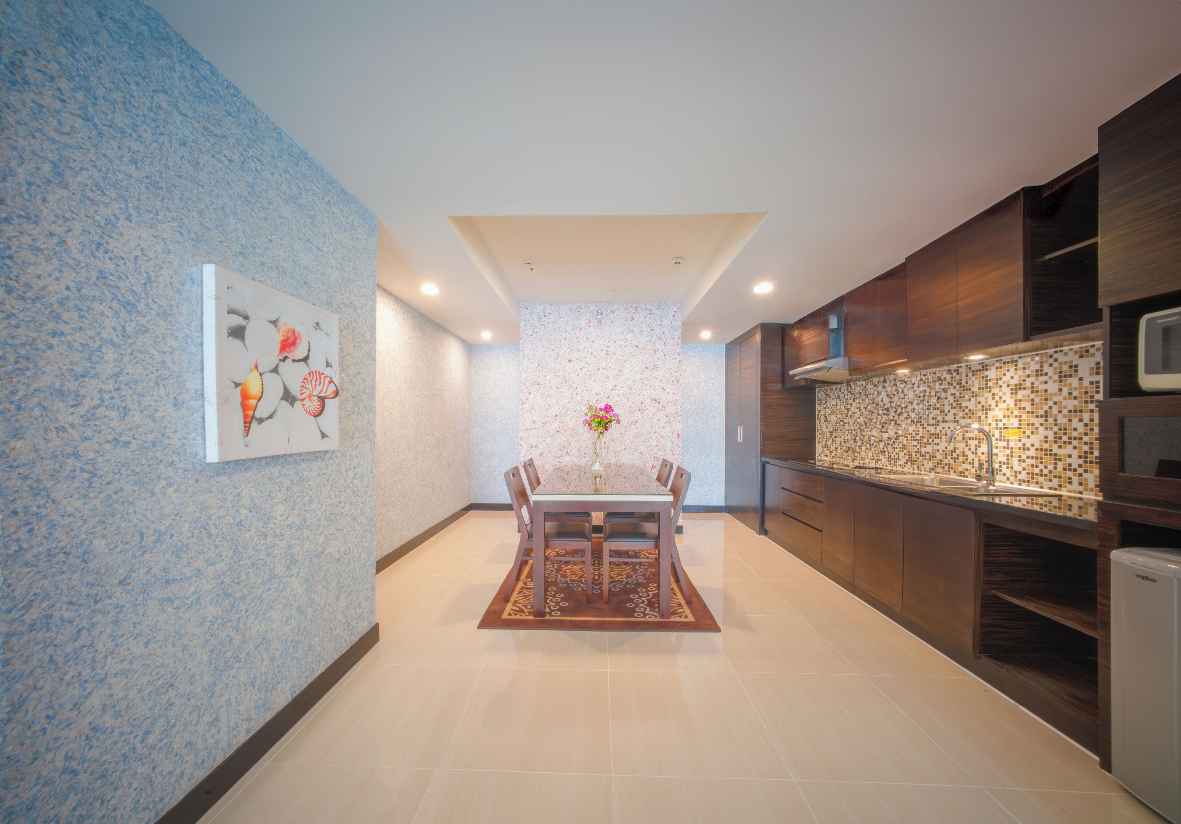 Una cocina moderna con comedor, que cuenta con un salpicadero de azulejos, armarios de madera y una isla central con un florero.