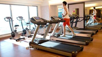 A gym with multiple treadmills, exercise bikes, and a large window providing natural light.