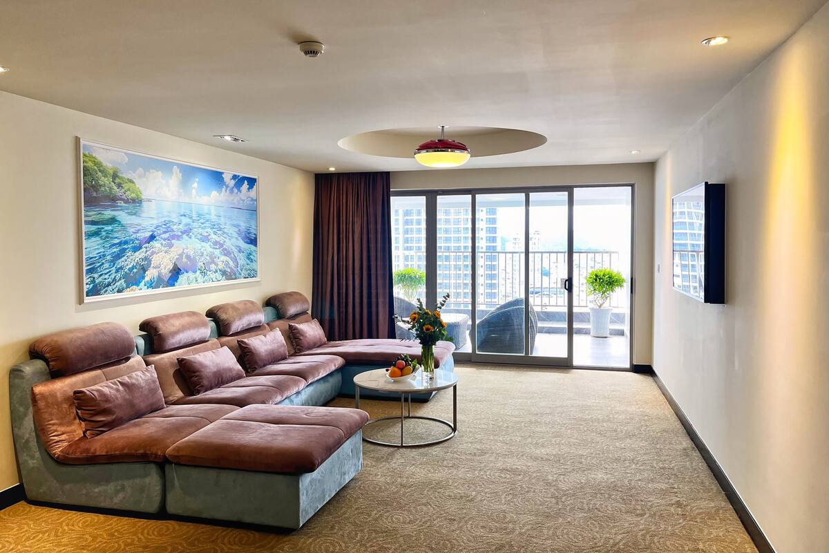 A modern living room with a sectional sofa, a round coffee table, and a large window with a view of buildings.