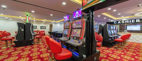 A casino with slot machines, red bar stools, and a cashier area.