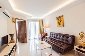 A modern living room with a leather sofa, a flat-screen TV, a coffee table, and decorative items.