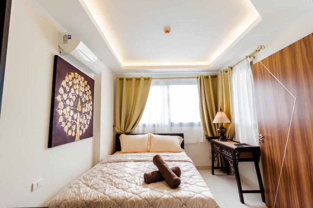 Une chambre d’hôtel avec un lit, un bureau, une lampe et un tableau au mur.