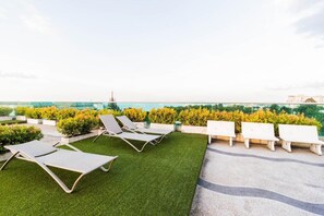 Relax on the rooftop terrace with city views, lounge chairs, and lush greenery.