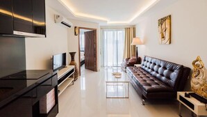 A modern living room with a flat-screen TV, a leather sofa, a coffee table, and a painting on the wall. - Club Royal Wongamat by PSR ASIA (Pattaya)