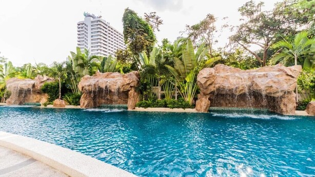 A swimming pool with rock formations and tropical vegetation. - Club Royal Wongamat by PSR ASIA (Pattaya)