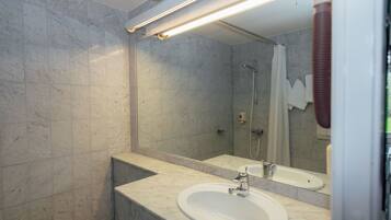 A modern bathroom with a marble sink, a large mirror, and a shower area.