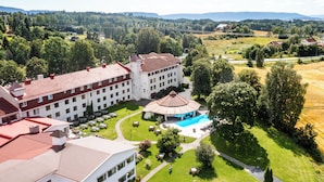 A large hotel with multiple buildings, a swimming pool, and surrounding greenery. - Klækken Hotell (Ringerike)