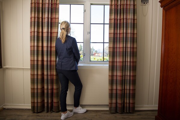 Una habitación con ventana, cortinas y una puerta.