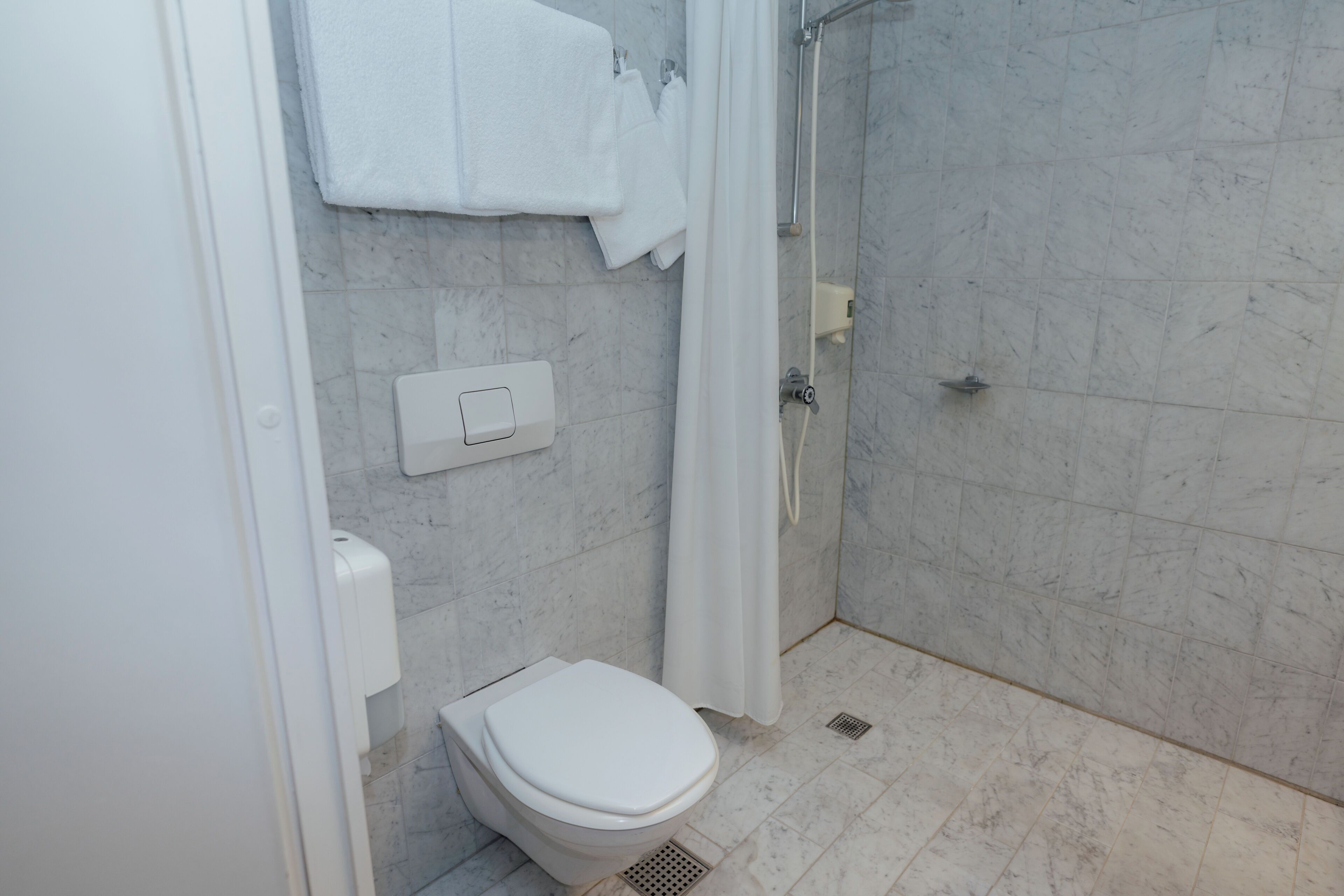 Ein Badezimmer mit Toilette, Dusche und Marmorboden.