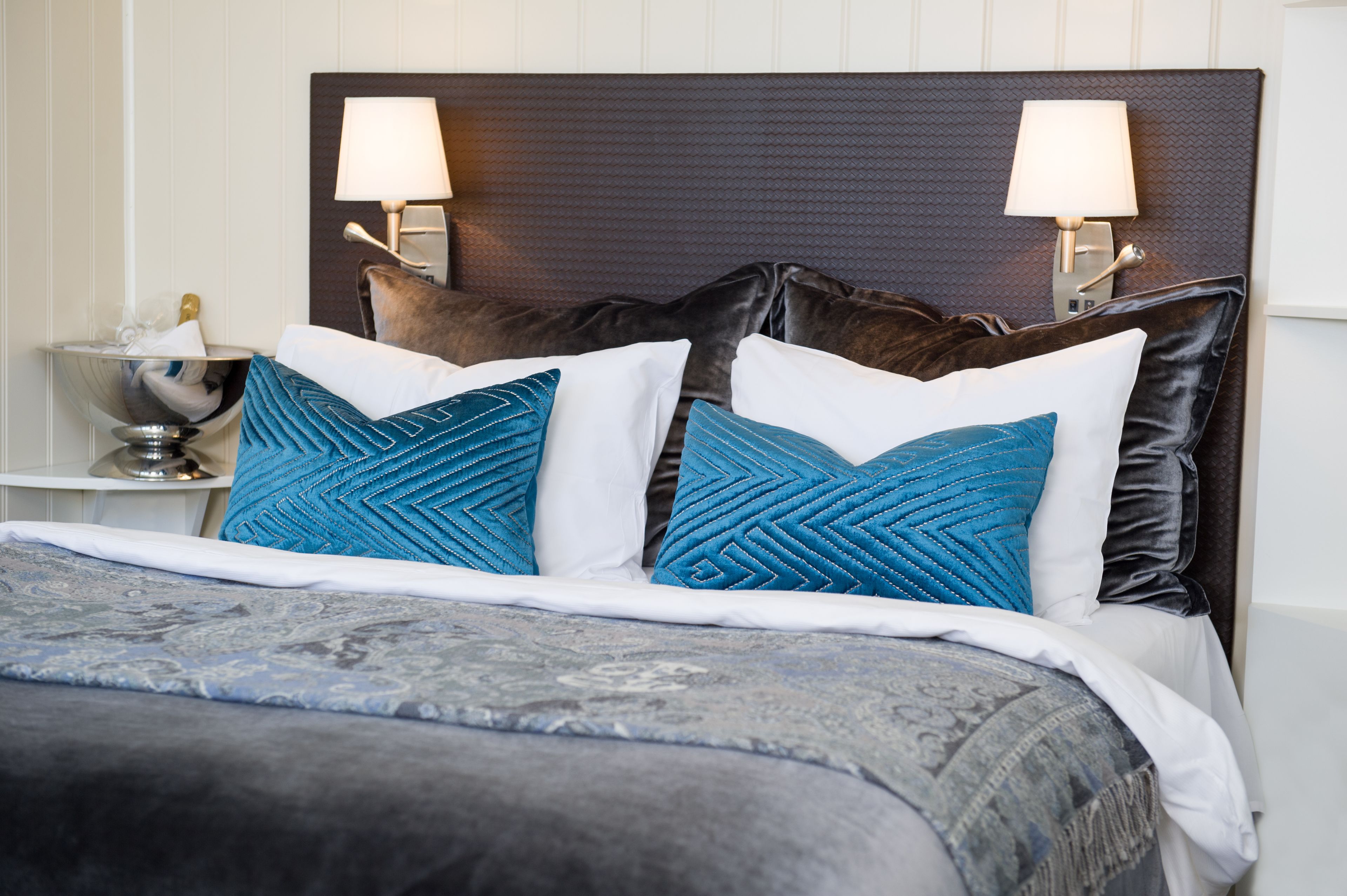 A neatly made bed with a patterned bedspread and two decorative pillows.