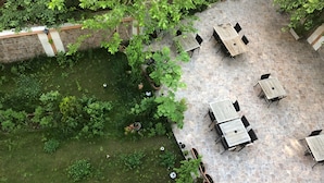 An outdoor patio with stone flooring, surrounded by lush greenery and potted plants.