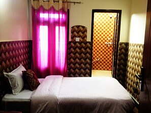 A bedroom with a bed, a nightstand, a mirror, and a door leading to a bathroom.