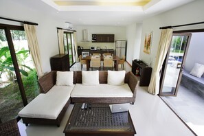 A modern living room with a sofa, a coffee table, and a dining area with a table and chairs.