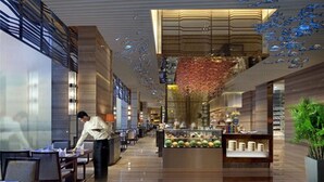 A spacious hotel lobby with a central island displaying fruits and beverages, a waiter attending to guests, and a modern architectural design with a high ceiling and decorative elements. - Sorl Hotel Hangzhou (Hangzhou)