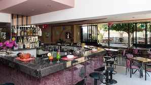 A bar area with a marble countertop, multiple stools, and a variety of bottles and glasses. - Villa George Studios (Rhodes)