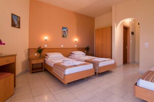 A hotel room with two single beds, a desk, a chair, and a small table.