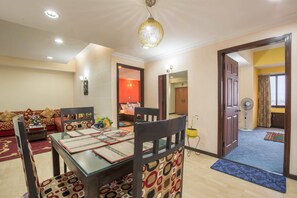 Un espace repas avec une table en verre, des chaises à motifs et un mur d’accent rouge.