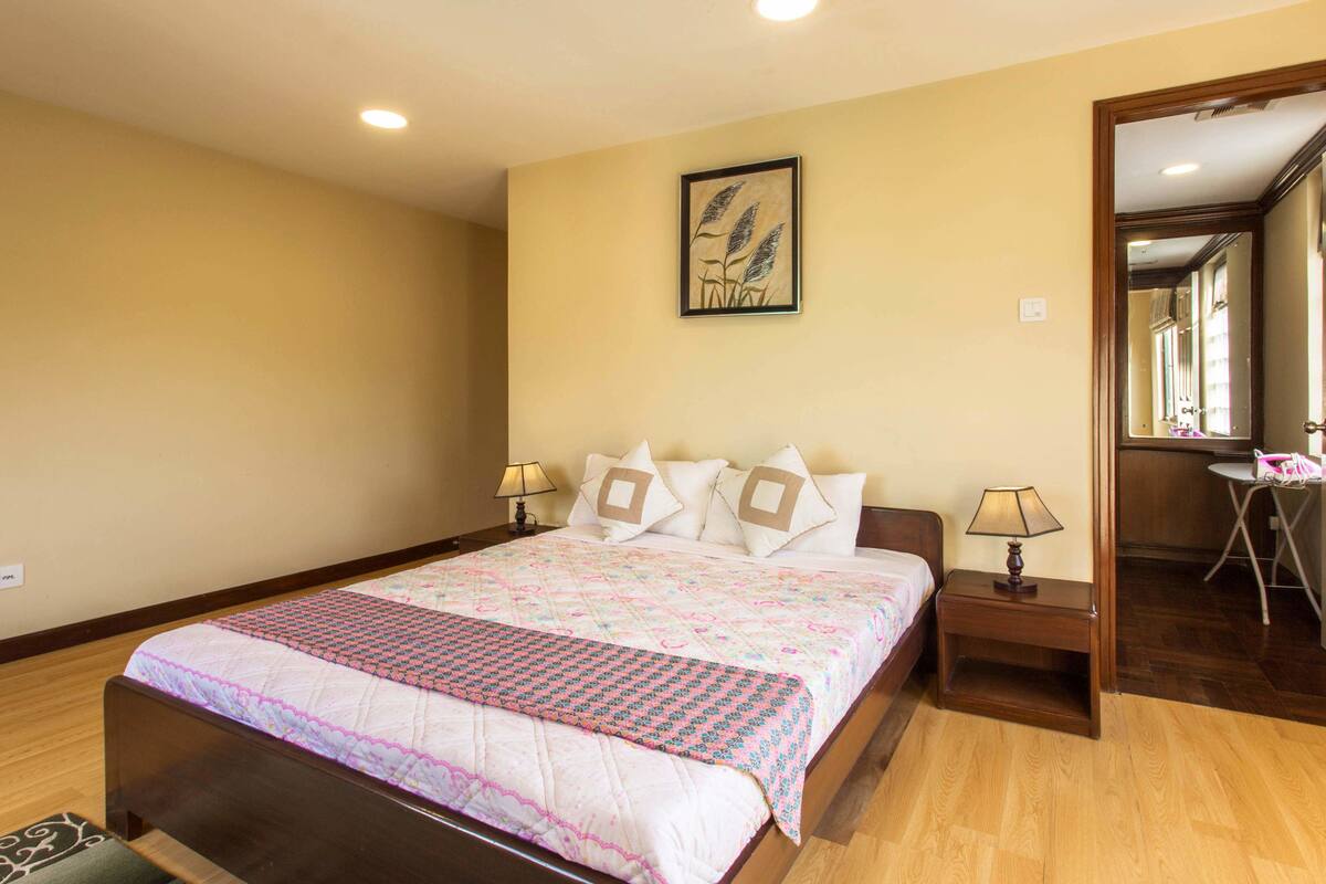 Un dormitorio con una cama grande, dos mesitas de noche, un espejo y un cuadro en la pared.