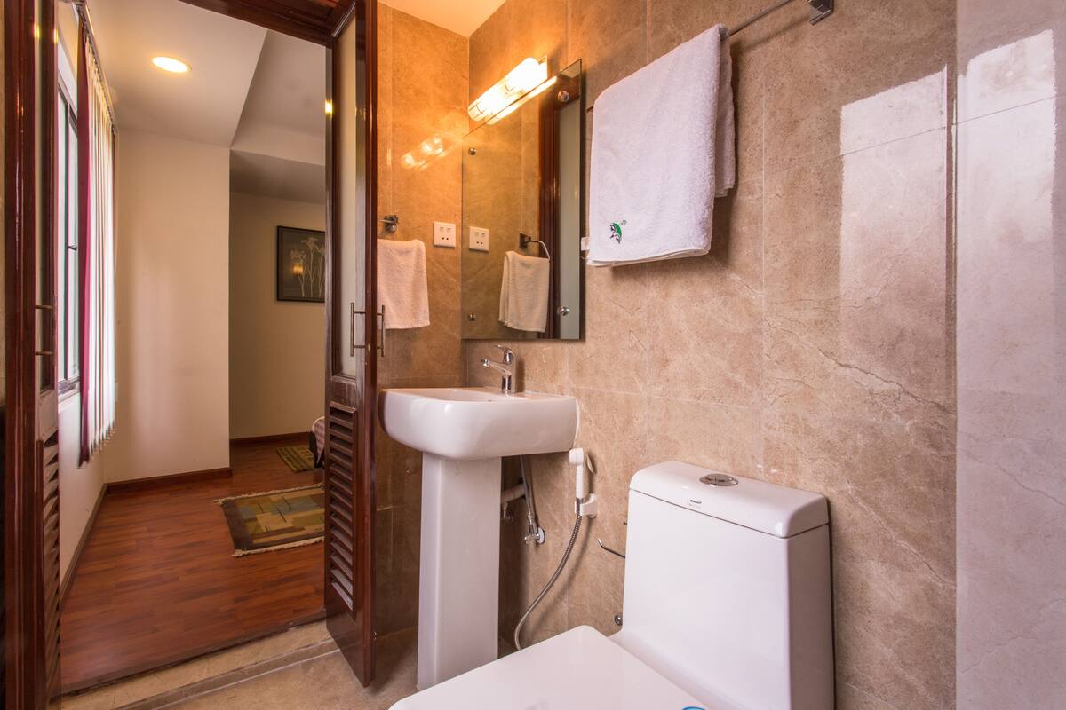 Un baño con lavamanos, espejo, toallero y retrete.