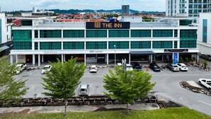 Un hôtel au design moderne, avec une enseigne bien visible indiquant « The Inn » et un parking où sont stationnées plusieurs voitures.