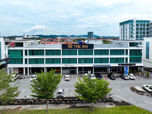 A hotel with a modern design, featuring a prominent sign for 'The Inn' and a parking lot with several cars. - The Inn Bintulu (Bintulu)