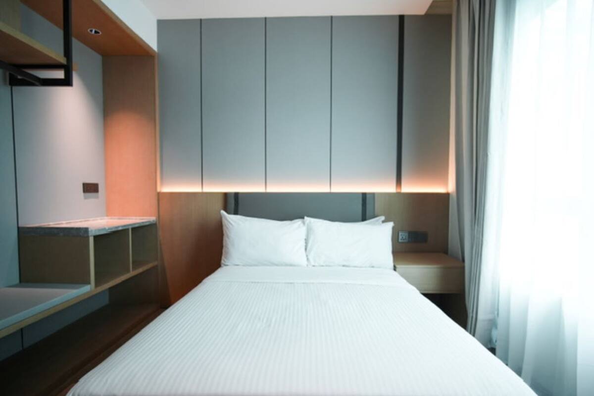 A modern hotel room with a large bed, built-in shelving, and a nightstand.