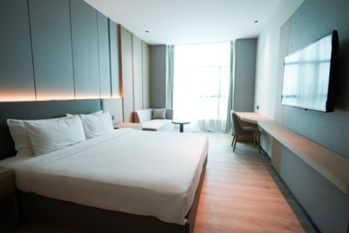 Habitación de hotel moderna con una cama grande, un escritorio y un televisor montado en la pared.