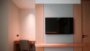 Une chambre moderne équipée d’un téléviseur à écran plat fixé au mur, d’un bureau en bois et d’une chaise.